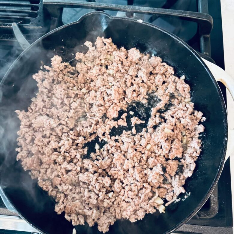 Ground pork being cooked in a saucepan to make dan dan noodles.