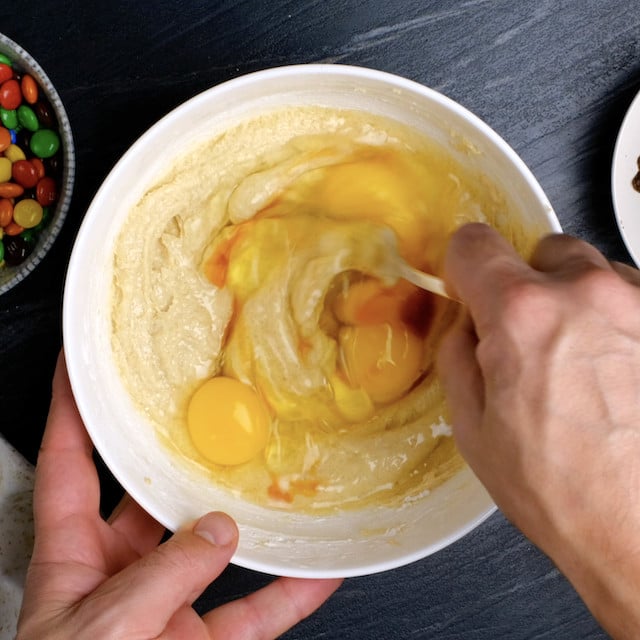 Eggs being mixed into softened butter and brown sugar mixture to make M&M chocolate chip cookies.
