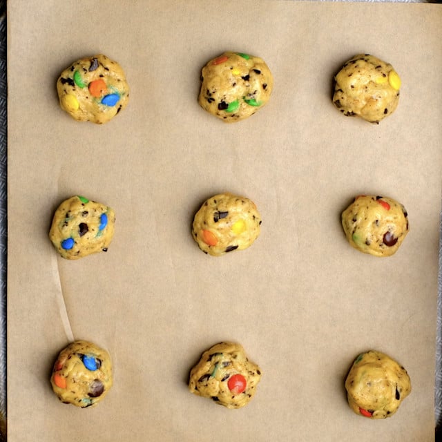 M&M chocolate chip cookie dough balls on a baking sheet lined with parchment paper.