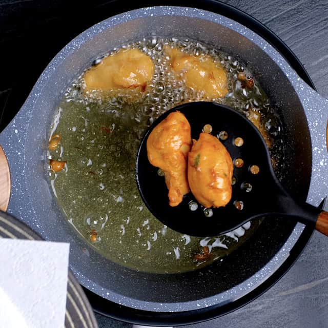 Chicken pieces being fried in hot oil until they're golden brown to make mochiko chicken.