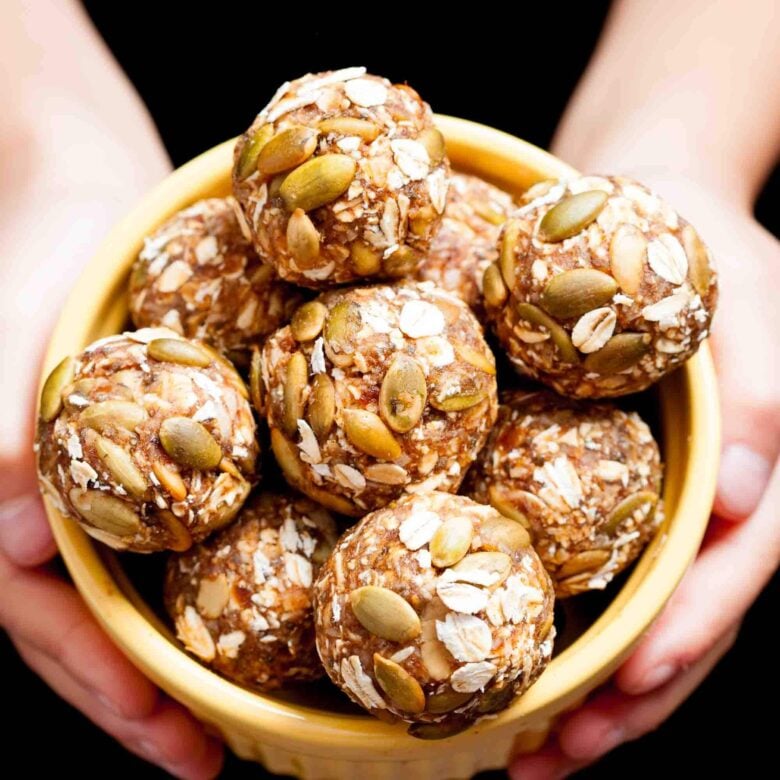 hands holding a bowl of pumpkin energy balls.