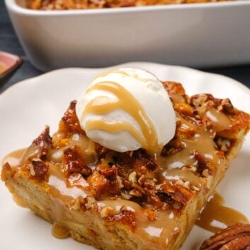A slice of pumpkin bread pudding topped with vanilla ice cream and caramel sauce, served on a white plate.