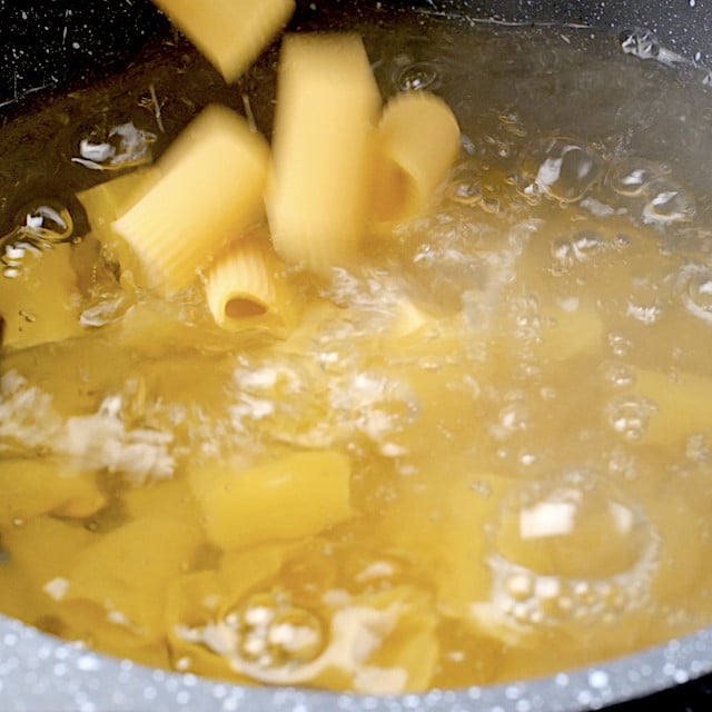 Rigatoni pasta being added to boiling water to make rigatoni bolognese.