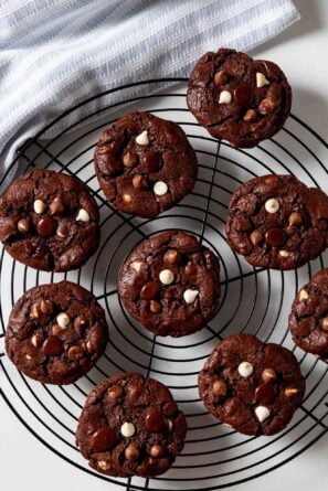 Overhead shot of freshly baked triple chocolate chip cookies on a wire rack.