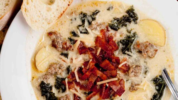 Overhead shot of homemade Zuppa Toscana soup, garnished with diced bacon and parmesan cheese.
