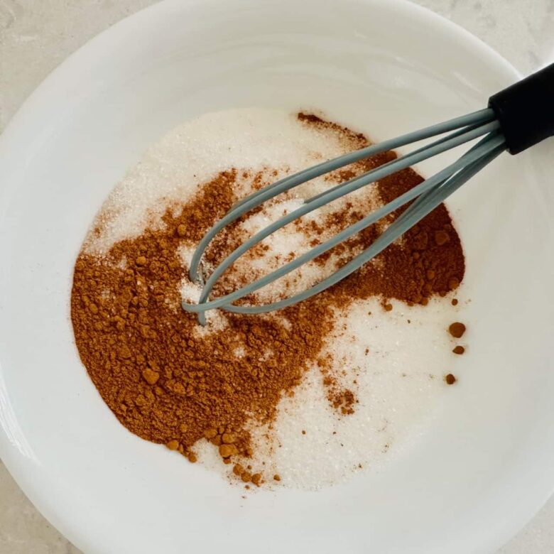 Cinnamon and sugar being whisked together to make cinnamon-sugar coating for chewy pumpkin snickerdoodles.