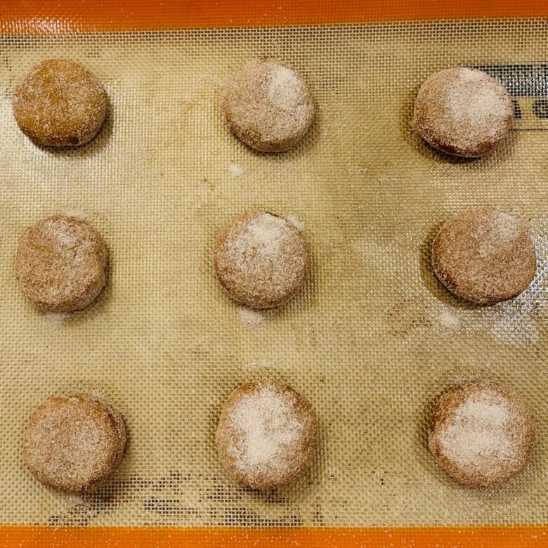 Chewy pumpkin snickerdoodles on a baking sheet being popping them into the oven.