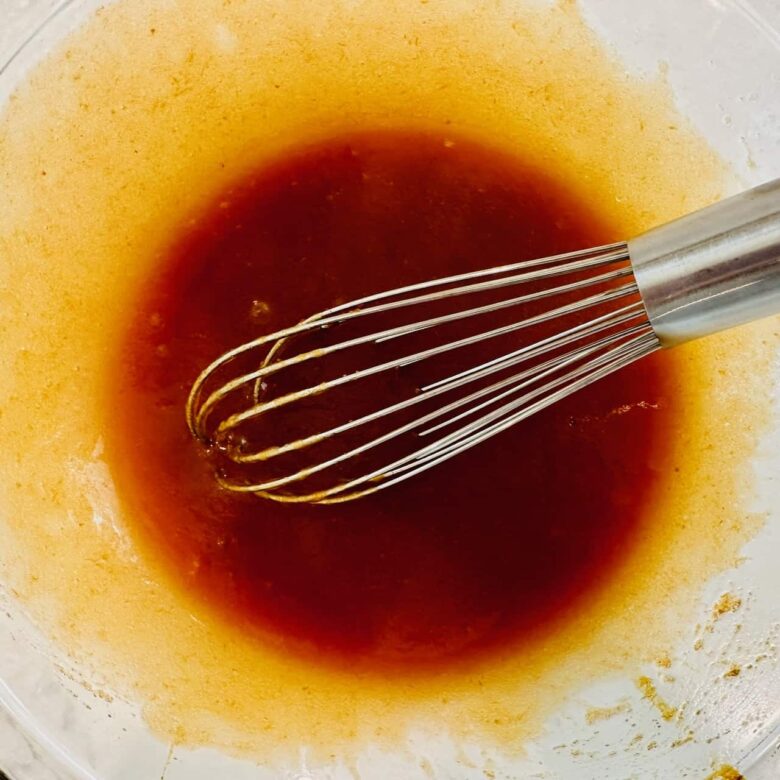 Wet ingredients to make pumpkin snickerdoodles being whisked in a glass bowl.