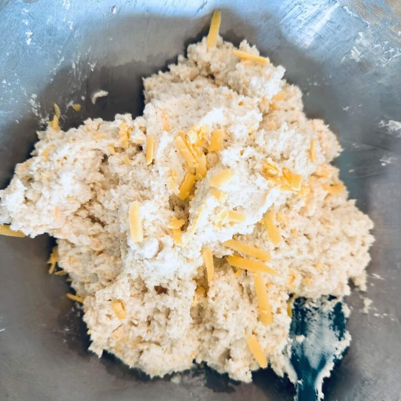 Cheddar bay biscuit dough being mixed together using a rubber spatula.