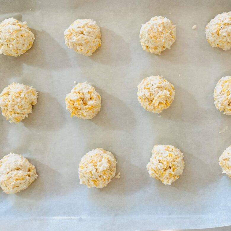Cheddar bay biscuit dough balls on a baking sheet lined with parchment paper.