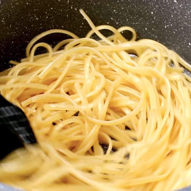 Boiled noodles being tossed with sesame oil to make chicken lo mein.