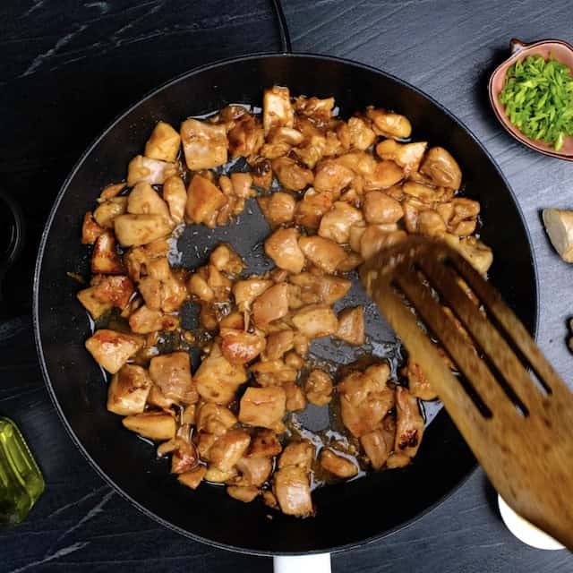 Marinated chicken being stir fried in a wok to make chicken lo mein.