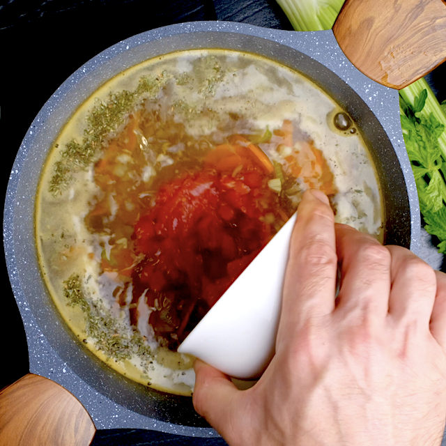 Diced tomatoes being added to soup mixture to make homemade chicken tortellini soup.