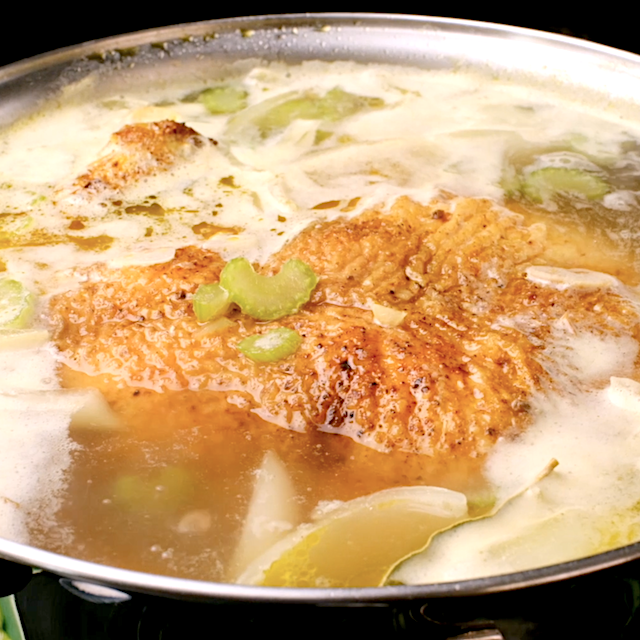 Chicken being simmered in a pot to make homemade chicken noodle soup.