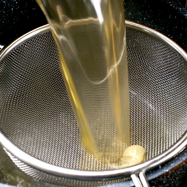 Chicken broth being strained to make homemade chicken noodle soup.