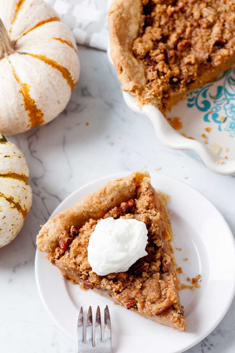 An overhead shot of a slice of pumpkin pie with streusel topping on a plate with a fork on the side.