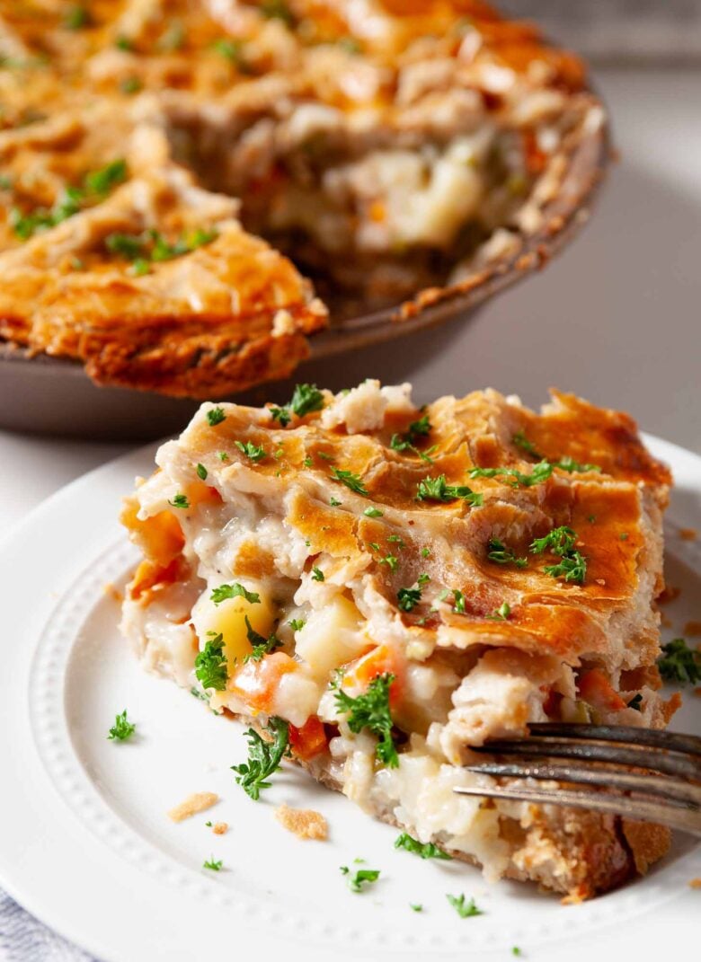 A slice of turkey pot pie on a white plate with a flaky crust.
