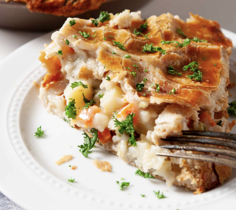 A closeup shot of a slice of turkey pot pie, garnished with fresh parsley.