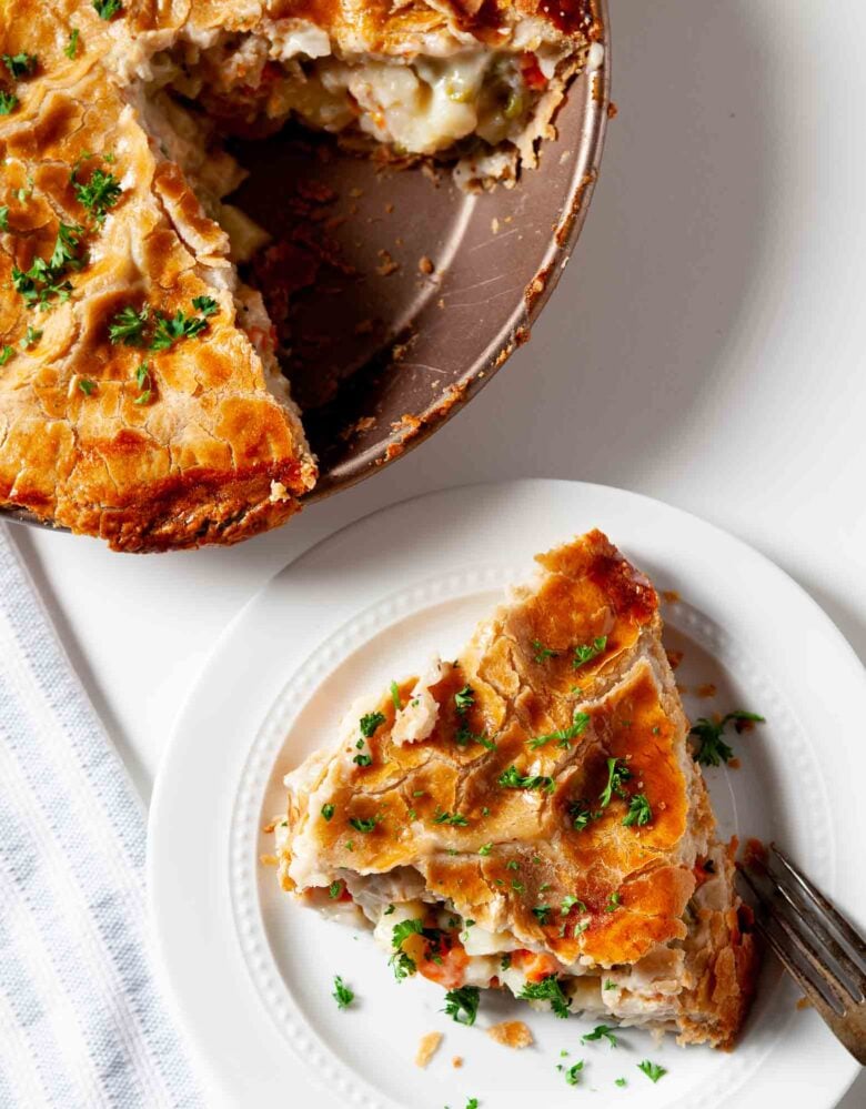 Overhead shot of a slice of turkey pot pie with a golden crust and parsley garnish.