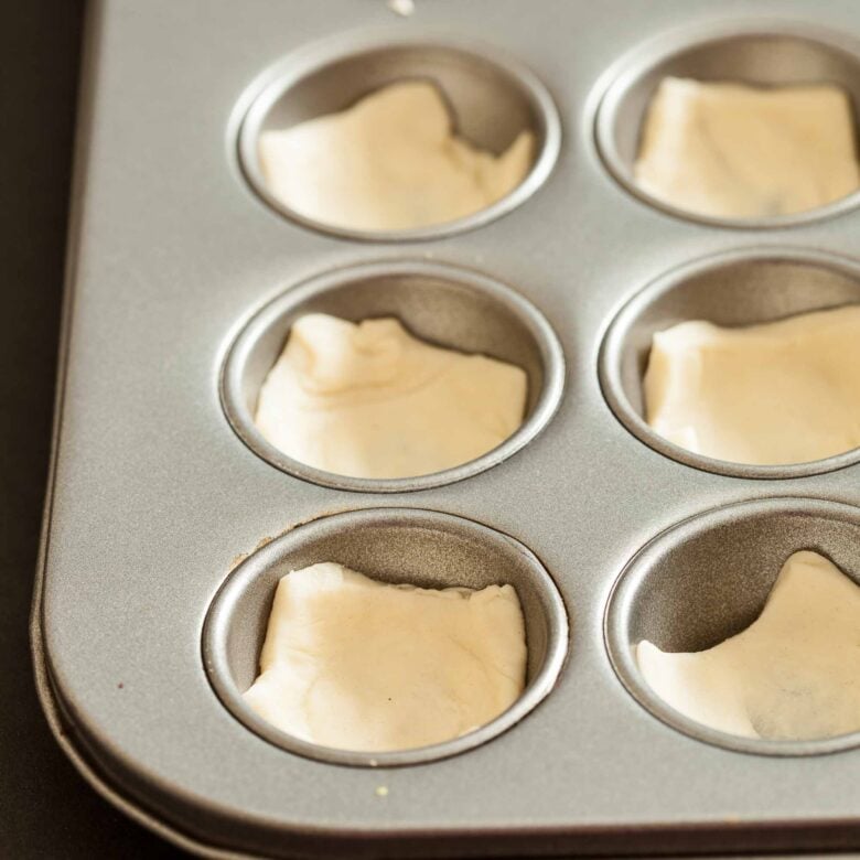 crescent dough pressed into mini muffin tin for cranberry brie bites.