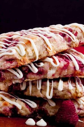 A stack of raspberry scones drizzled with white chocolate.