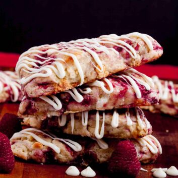 A stack of raspberry scones drizzled with white chocolate.