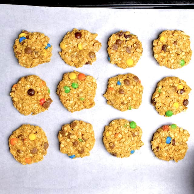 Overhead shot of monster cookies on a baking sheet lined with parchment paper, ready to be baked.