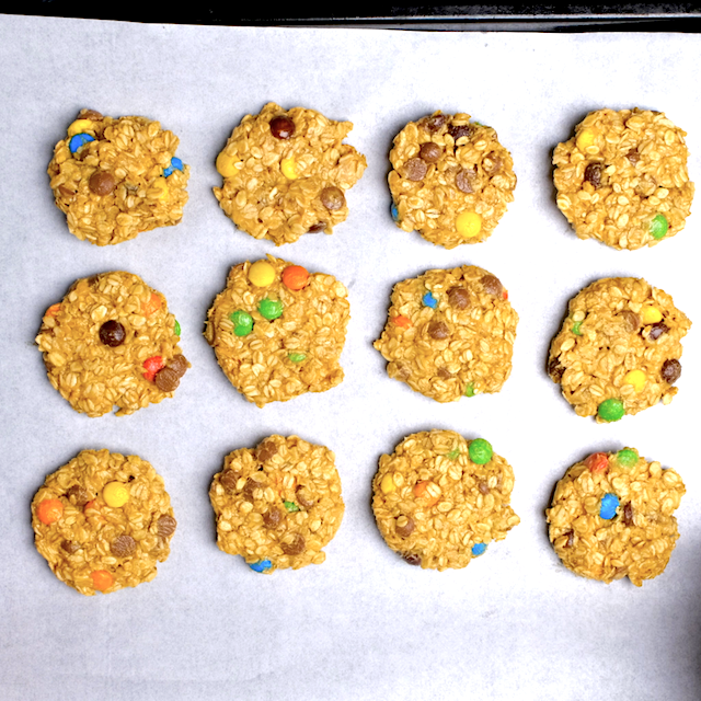 Overhead shot of monster cookies on a baking sheet lined with parchment paper, ready to be baked.