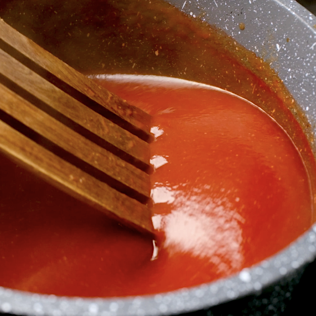 Sweet and sour sauce being thickened in a saucepan.