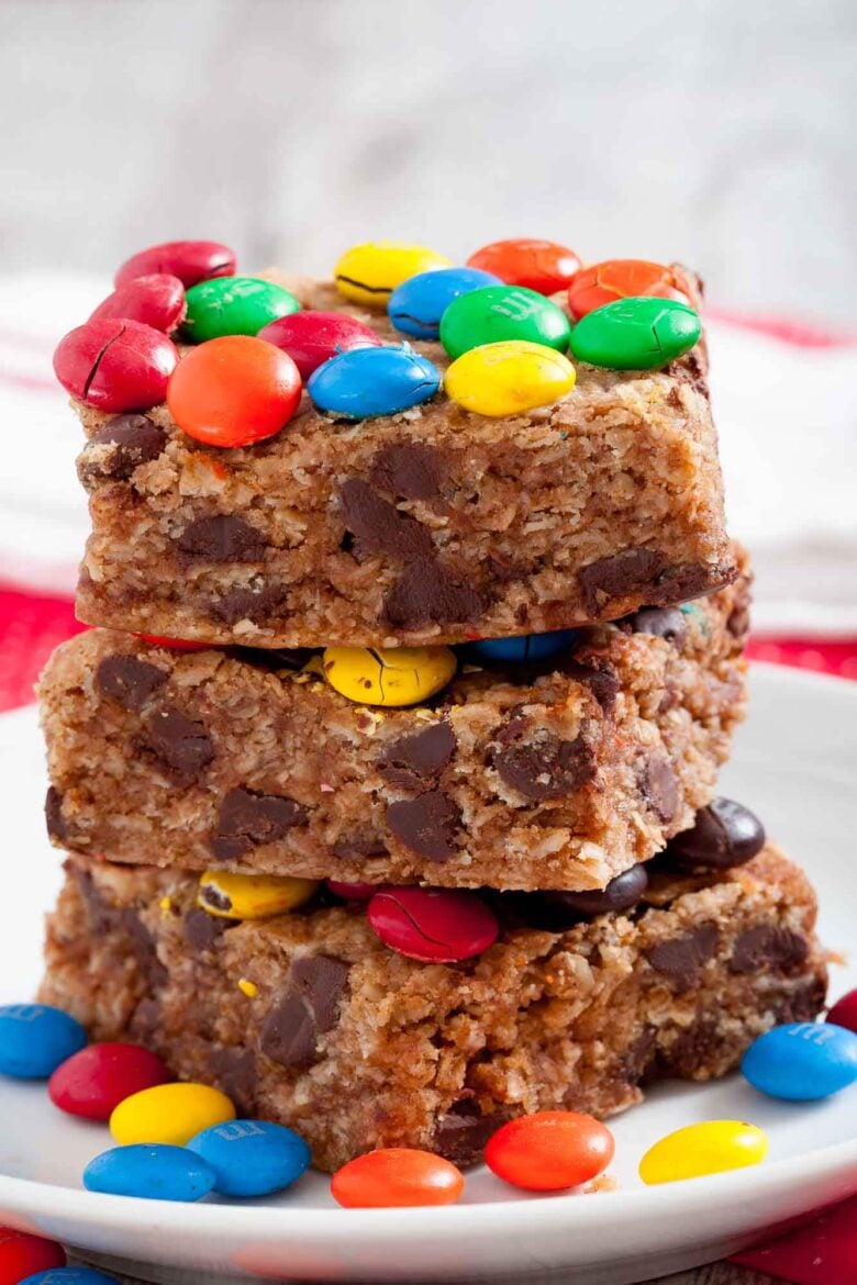 Closeup shot of three stacked monster cookie bars with chocolate chips and colorful M&Ms on top.