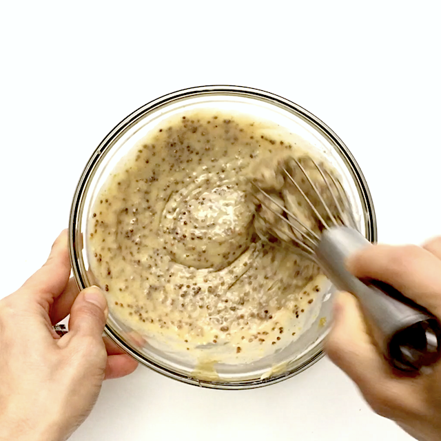 Ingredients to make honey mustard sauce being whisked in a glass bowl.