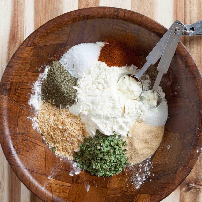 Overhead shot of a brown bowl with all-natural ingredients to make homemade ranch seasoning.