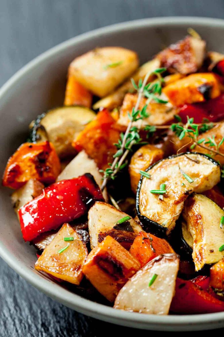 A closeup shot of a bowl of easy roasted vegetables with fresh herbs.