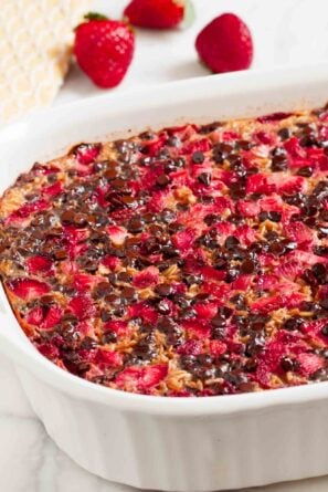 Closeup shot of chocolate baked oatmeal with strawberries in a white baking dish.