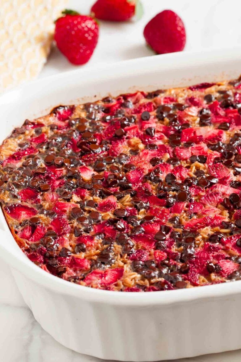 Closeup shot of chocolate baked oatmeal with strawberries in a white baking dish.