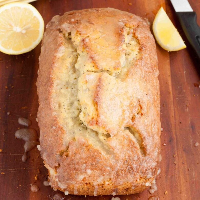 Overhead shot of lemon poppy seed bread with a glazed topping, on a wooden surface.