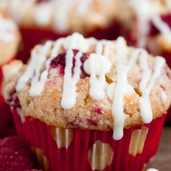 Close-up of a white chocolate raspberry muffin drizzled with white chocolate.