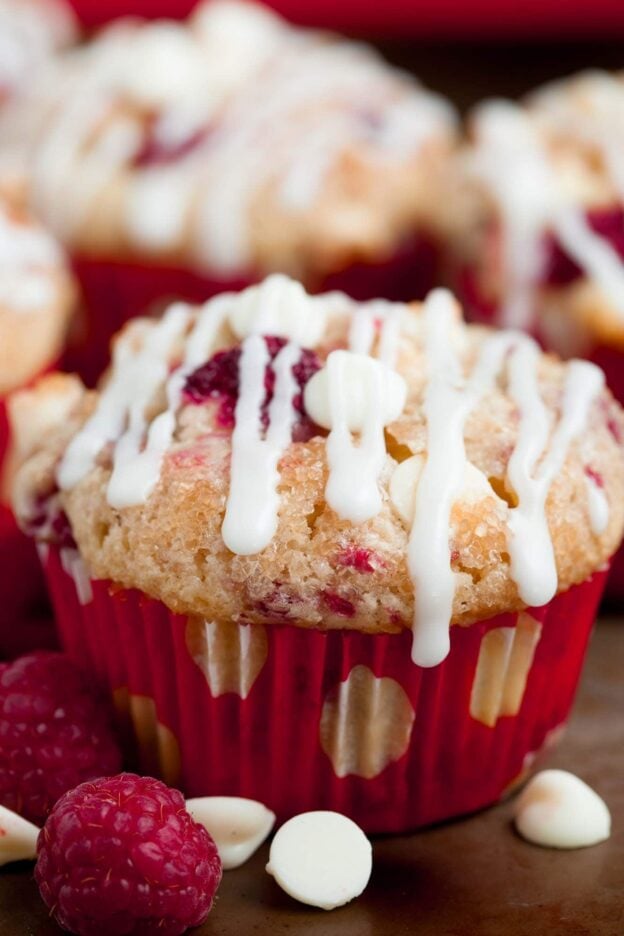 Close-up of a white chocolate raspberry muffin drizzled with white chocolate.