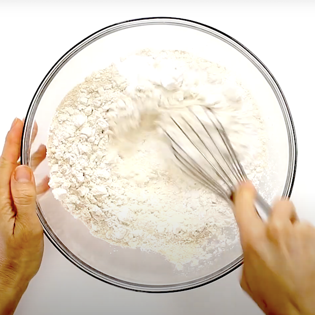 Dry ingredients to make coconut pancakes being mixed in a glass bowl.