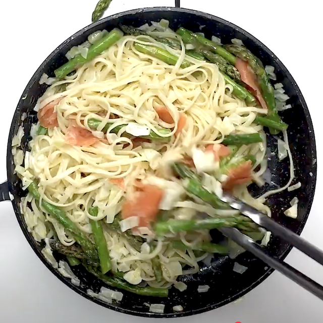 Asparagus and smoked salmon added to a pan to make lemon salmon pasta.
