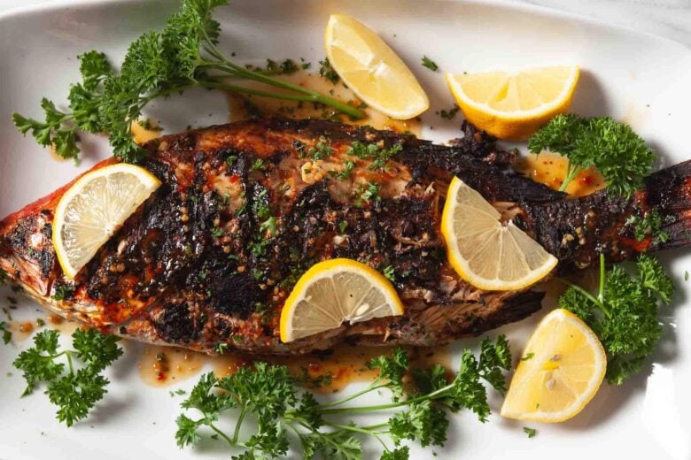 grilled whole red snapper on white plate horizontal shot
