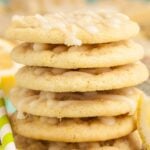 A stack of soft lemon cookies with lemon icing, sitting on a burlap cloth.