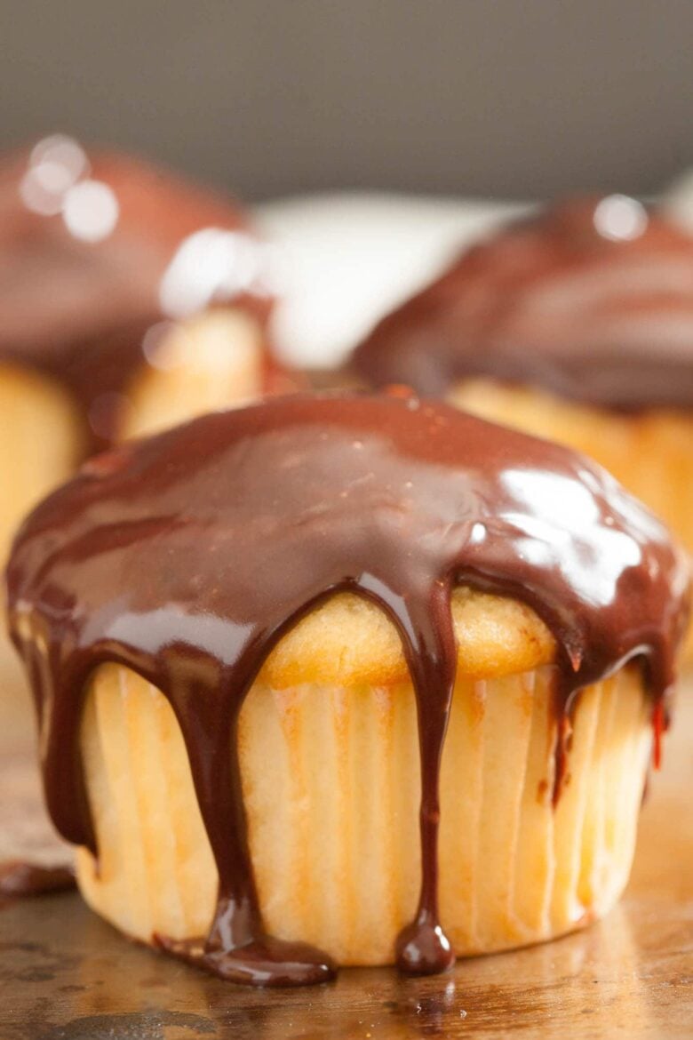 Closeup shot of a boston cream cupcake with shiny chocolate glaze on top.