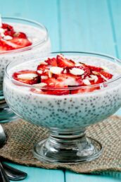 A glass dish filled with chia seed pudding topped with sliced strawberries and almonds.