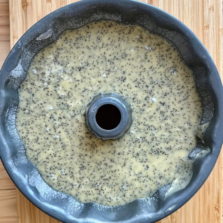 Poppy seed cake batter poured into a greased bundt pan, ready to be baked.
