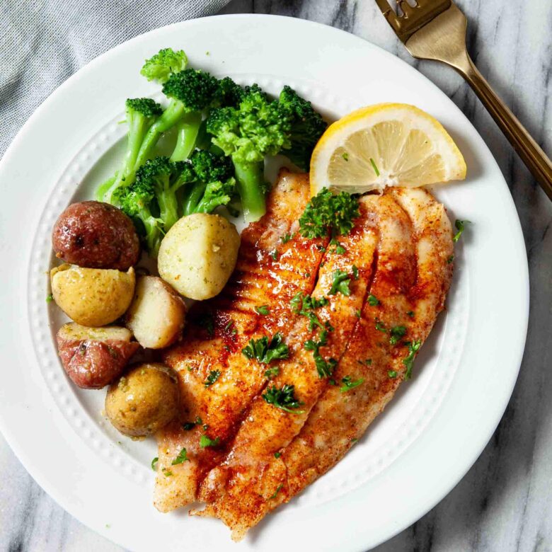Overhead shot of crispy air fryer tilapia with roasted potatoes and broccoli.