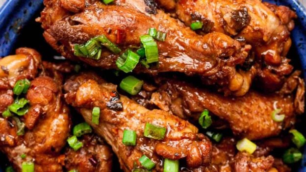 Overhead shot of braised Asian chicken wings, garnished with chopped green onions.
