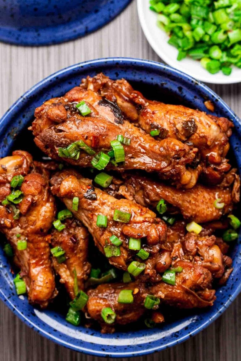 Overhead shot of braised Asian chicken wings, garnished with chopped green onions.
