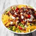 Closeup shot of BBQ chicken salad with bbq and ranch sauce on top.