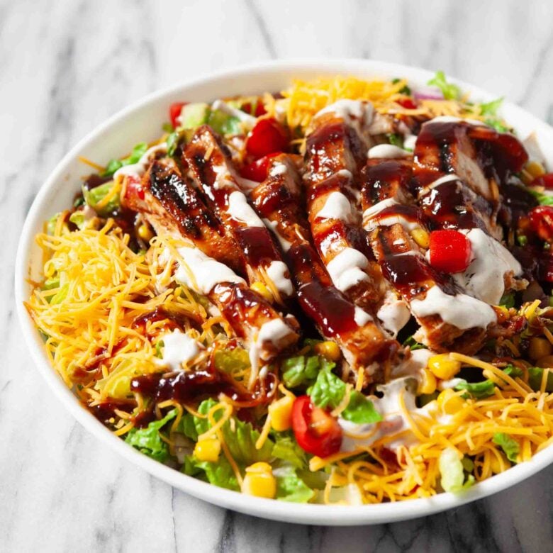 Closeup shot of BBQ chicken salad with bbq and ranch sauce on top.